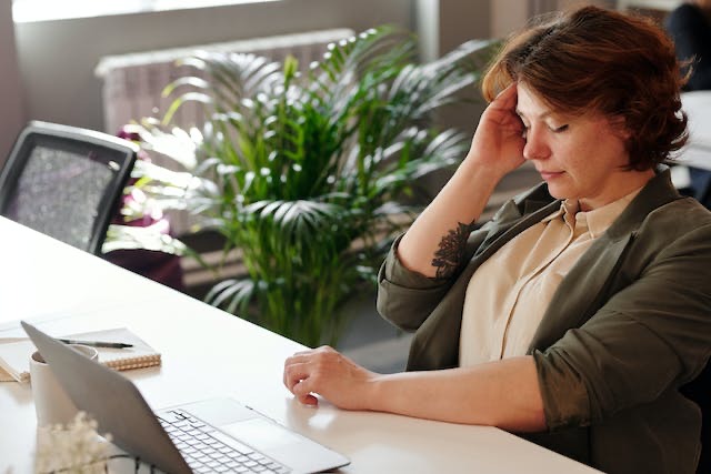 woman with headache rubbing head at desk